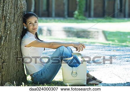 Woman sitting on ground, leaning against tree View Large Photo Image Stock Photo - Woman sitting on ground, leaning against tree. Fotosearch