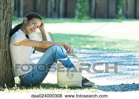 Woman sitting on ground, leaning against tree View Large Photo Image Stock Photo - Woman sitting on ground, leaning against tree. Fotosearch