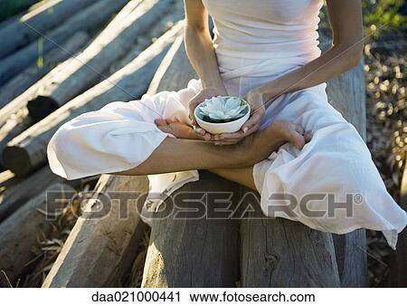 Woman sitting on pile of logs, holding bowl with lotus flower, chest down View Large Photo Image Stock Image - Woman sitting on pile of logs, holding bowl with lotus flower, chest down. Fotosearch