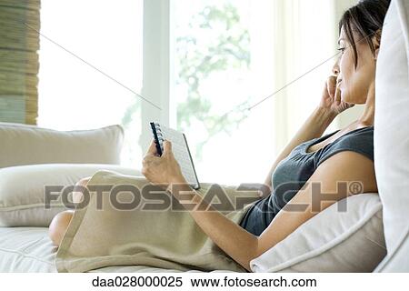 Woman sitting on sofa, looking at calendar in agenda View Large Photo Image Stock Photography - Woman sitting on sofa, looking at calendar in agenda. Fotosearch