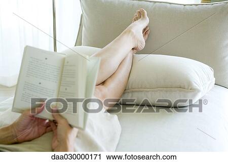 Woman sitting on sofa, reading book, cropped view View Large Photo Image Stock Image - Woman sitting on sofa, reading book, cropped view. Fotosearch
