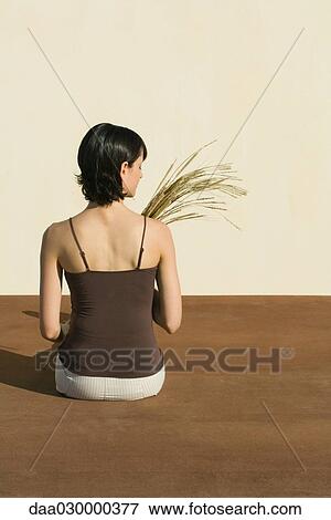 Woman sitting on the ground, holding wheat, rear view View Large Photo Image Stock Photo - Woman sitting on the ground, holding wheat, rear view. Fotosearch