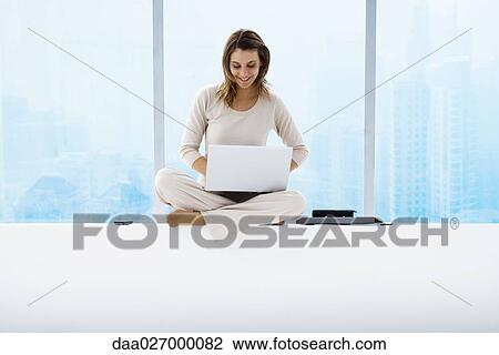 Woman sitting on windowsill using laptop, high rises in background View Large Photo Image Stock Image - Woman sitting on windowsill using laptop, high rises in background. Fotosearch