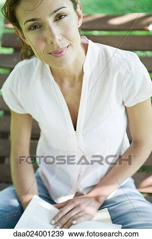 Woman sitting with book, looking at camera View Large Photo Image Stock Photo - Woman sitting with book, looking at camera. Fotosearch