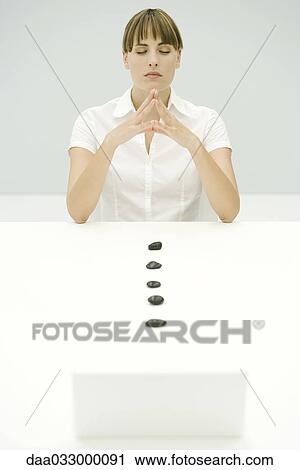 Woman sitting with eyes closed and hands clasped, line of stones leading to laptop View Large Photo Image Stock Image - Woman sitting with eyes closed and hands clasped, line of stones leading to laptop. Fotosearch