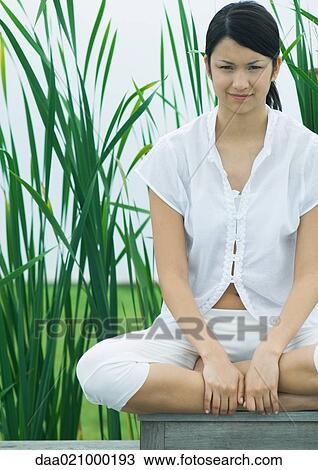 Woman sitting with legs crossed, looking at camera View Large Photo Image Stock Image - Woman sitting with legs crossed, looking at camera. Fotosearch