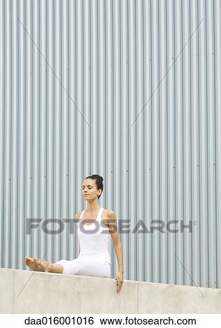 Stock Photograph - Woman sitting with legs straight out, eyes closed. Fotosearch