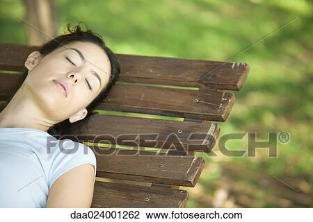 Stock Image - Woman sleeping on bench, cropped. Fotosearch
