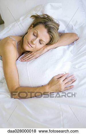 Stock Photo - Woman sleeping on comfortable pillow, high angle view. Fotosearch