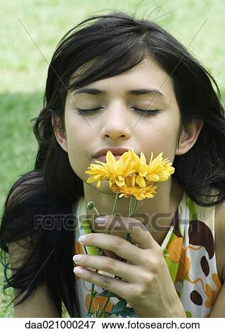 Stock Photo - Woman smelling flowers, eyes closed. Fotosearch