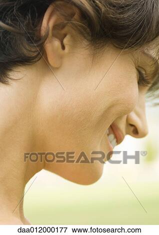 Stock Photo - Woman smiling and looking down, close up side view of face. Fotosearch