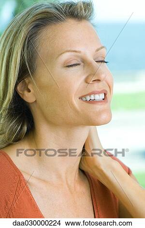 Woman smiling, holding neck, eyes closed View Large Photo Image Picture - Woman smiling, holding neck, eyes closed. Fotosearch