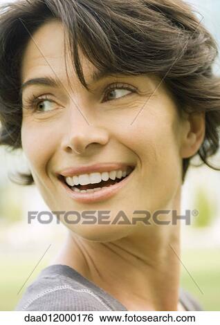 Stock Photograph - Woman smiling over shoulder, close-up of head, portrait. Fotosearch