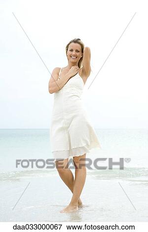 Woman standing at the beach in the surf, smiling at camera View Large Photo Image Stock Photo - Woman standing at the beach in the surf, smiling at camera. Fotosearch