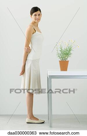 Woman standing beside potted chamomile plant, smiling at camera View Large Photo Image Stock Image - Woman standing beside potted chamomile plant, smiling at camera. Fotosearch