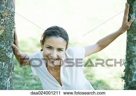 Woman standing between wooden posts, smiling at camera View Large Photo Image Stock Image - Woman standing between wooden posts, smiling at camera. Fotosearch