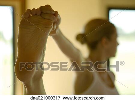 Woman standing, holding up foot View Large Photo Image Stock Photo - Woman standing, holding up foot. Fotosearch