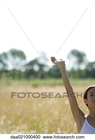 Woman standing in field with arm up, cropped view View Large Photo Image Stock Image - Woman standing in field with arm up, cropped view. Fotosearch
