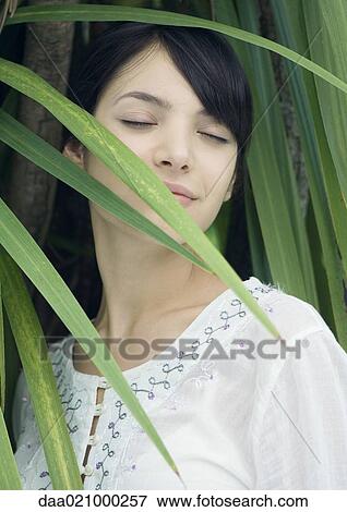 Woman standing in lush foliage, eyes closed, smiling View Large Photo Image Stock Photo - Woman standing in lush foliage, eyes closed, smiling. Fotosearch