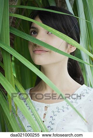 Stock Photography - Woman standing in lush foliage, looking up. Fotosearch