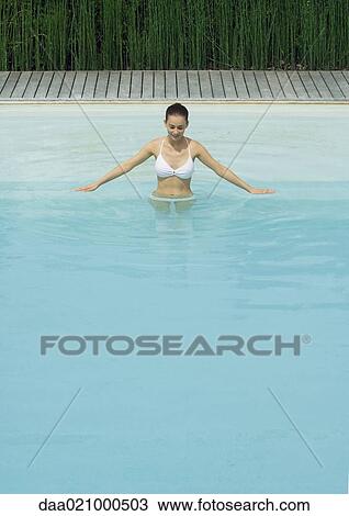 Woman standing in pool with arms out, looking down, smiling View Large Photo Image Stock Image - Woman standing in pool with arms out, looking down, smiling. Fotosearch