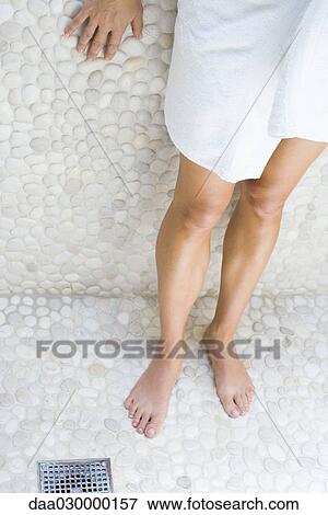 Stock Photo - Woman standing in shower, wrapped in towel, cropped view. Fotosearch