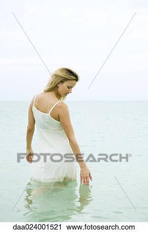 Woman standing knee deep in ocean, touching surface of water View Large Photo Image Stock Image - Woman standing knee deep in ocean, touching surface of water. Fotosearch
