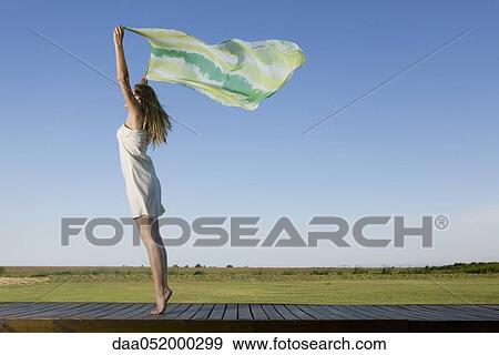 Woman standing on deck, holding scarf up in breeze View Large Photo Image Stock Photo - Woman standing on deck, holding scarf up in breeze. Fotosearch