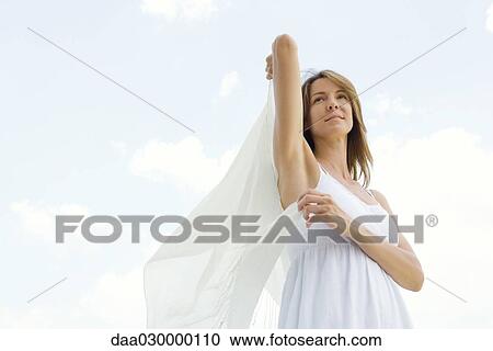 Woman standing outdoors, holding up shawl, low angle view View Large Photo Image Stock Image - Woman standing outdoors, holding up shawl, low angle view. Fotosearch