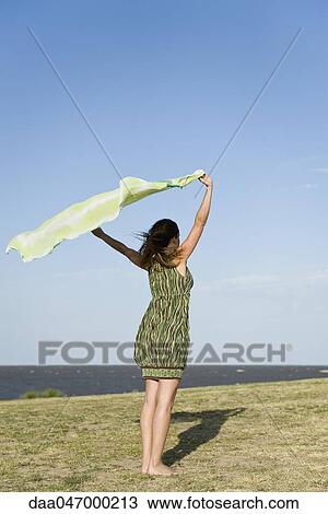 Woman standing outdoors, holding up shawl in wind, full length View Large Photo Image Stock Image - Woman standing outdoors, holding up shawl in wind, full length. Fotosearch