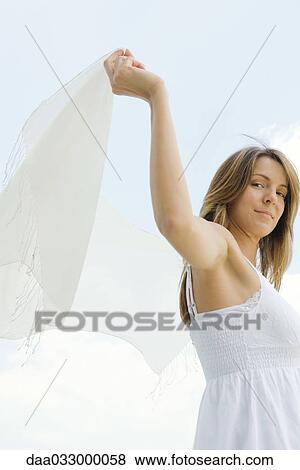 Woman standing outdoors, holding up shawl, low angle view View Large Photo Image Stock Photo - Woman standing outdoors, holding up shawl, low angle view. Fotosearch