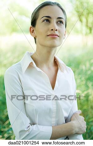 Picture - Woman standing outdoors, waist up, smiling, portrait. Fotosearch