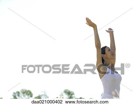 Woman standing outdoors with arms up, low angle view View Large Photo Image Stock Image - Woman standing outdoors with arms up, low angle view. Fotosearch