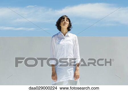Woman standing outdoors with eyes closed, head back, smiling View Large Photo Image Picture - Woman standing outdoors with eyes closed, head back, smiling. Fotosearch