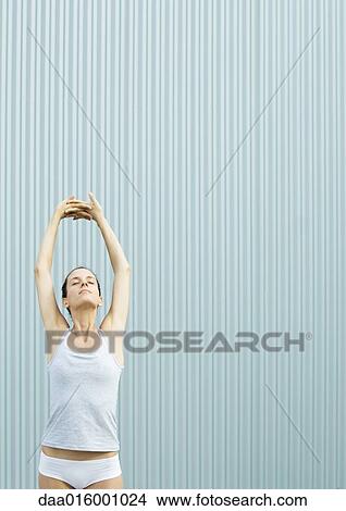Picture - Woman standing stretching arms over head. Fotosearch