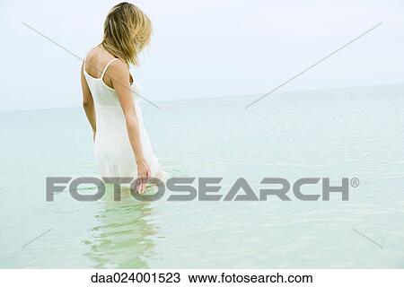 Woman standing thigh deep in ocean, touching surface of water View Large Photo Image Stock Image - Woman standing thigh deep in ocean, touching surface of water. Fotosearch