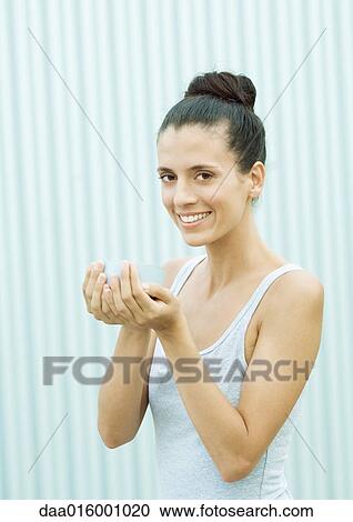 Stock Image - Woman standing with bowl in hands, smiling at camera. Fotosearch