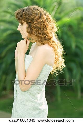 Stock Photography - Woman standing, wrapped in towel, side view. Fotosearch