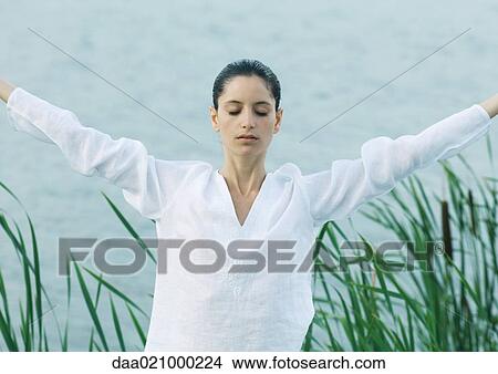Woman stretching arms, lake in background View Large Photo Image Picture - Woman stretching arms, lake in background. Fotosearch