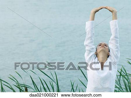 Woman stretching arms over head, lake in background View Large Photo Image Stock Image - Woman stretching arms over head, lake in background. Fotosearch