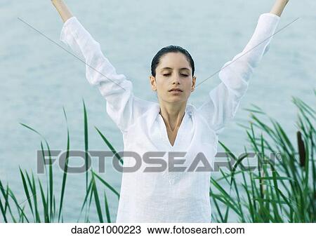 Woman stretching arms over head, lake in background View Large Photo Image Stock Image - Woman stretching arms over head, lake in background. Fotosearch