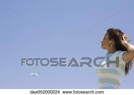 Woman stretching outdoors, listening to earphones View Large Photo Image Picture - Woman stretching outdoors, listening to earphones. Fotosearch