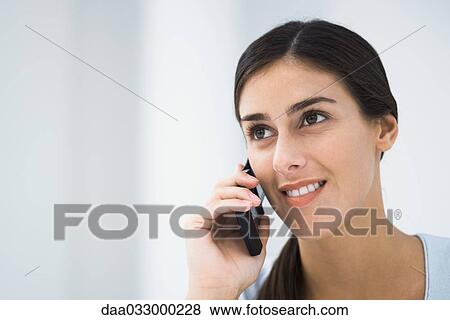 Stock Photo - Woman talking on cell phone, smiling and looking away. Fotosearch