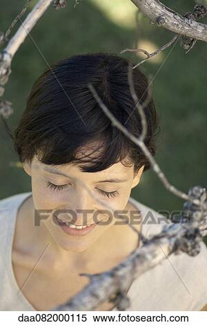 Woman under tree branches with eyes closed, smiling View Large Photo Image Stock Photography - Woman under tree branches with eyes closed, smiling. Fotosearch