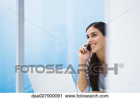 Woman using cell phone and laptop, smiling, cropped view View Large Photo Image Stock Image - Woman using cell phone and laptop, smiling, cropped view. Fotosearch