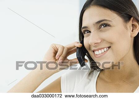 Woman using cell phone, looking up and smiling View Large Photo Image Stock Image - Woman using cell phone, looking up and smiling. Fotosearch