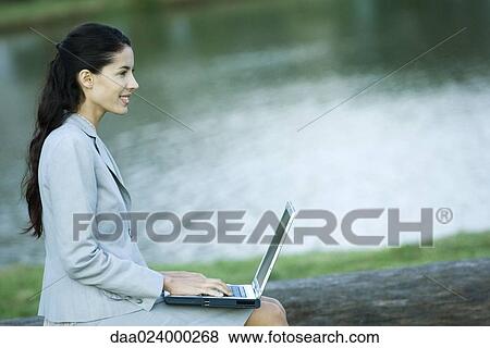 Woman using laptop, lake in background View Large Photo Image Stock Photo - Woman using laptop, lake in background. Fotosearch