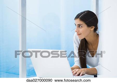 Woman using laptop, looking out window, cropped View Large Photo Image Stock Image - Woman using laptop, looking out window, cropped. Fotosearch