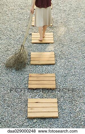 Woman walking along footpath in gravel, pulling branch behind her, high angle view, cropped View Large Photo Image Stock Photo - Woman walking along footpath in gravel, pulling branch behind her, high angle view, cropped. Fotosearch