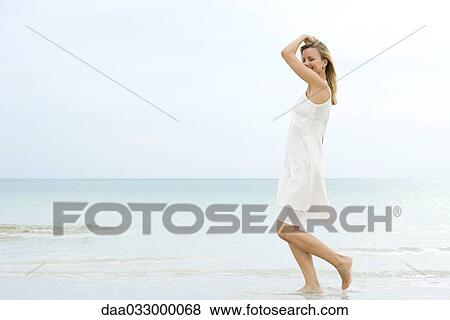Woman walking at the beach in the surf, smiling, side view View Large Photo Image Stock Photo - Woman walking at the beach in the surf, smiling, side view. Fotosearch